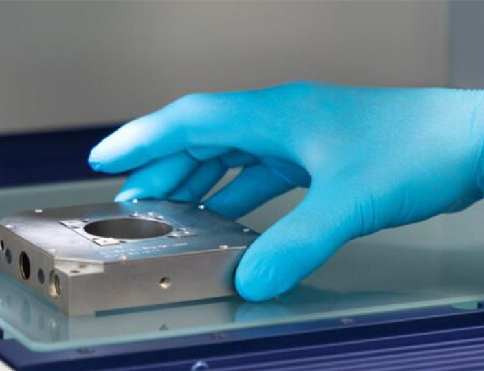 An operator places a Queensgate piezo nanopositioning stage on a glass plate.